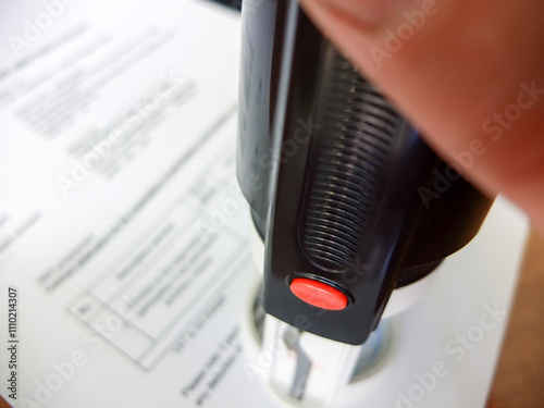 Close-up of a man putting a stamp on a document. Business concept photo