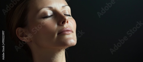 Elegant portrait of a serene woman in her thirties with closed eyes against a dark background showcasing beauty and tranquility. photo