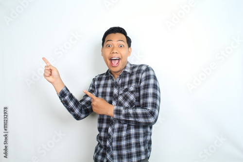 surprised and shock asian man pointing hand to copy space wearing casual plaid shirt isolated on white