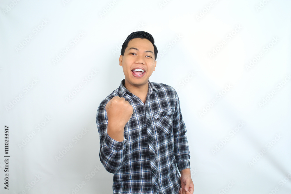 cheerful asian man raising fist showing winning and success gesture expression wearing casual shirt isolated on white cheerful asian man raising fist showing winning and success gesture expression wearing casual shirt isolated on white