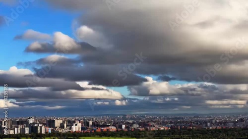 A time lapse Clouds moving above a cityscape with green parks in view