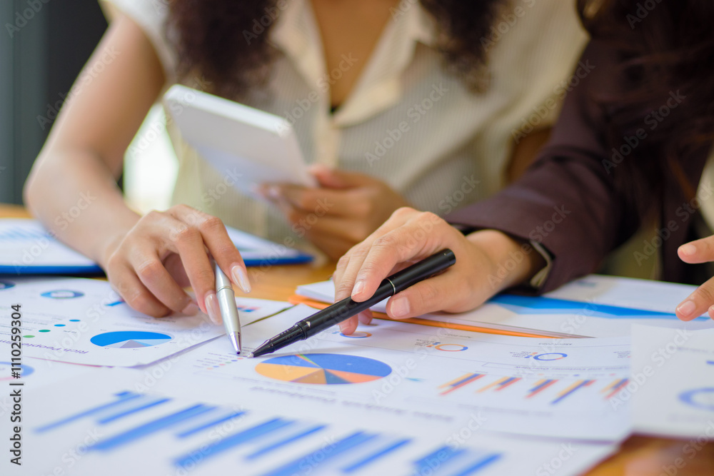 Two beautiful young businesswomen using a calculator to calculate and analyze a real estate project that they are looking for. Two beautiful young businesswomen using a calculator to calculate and analyze a real estate project that they are looking for.