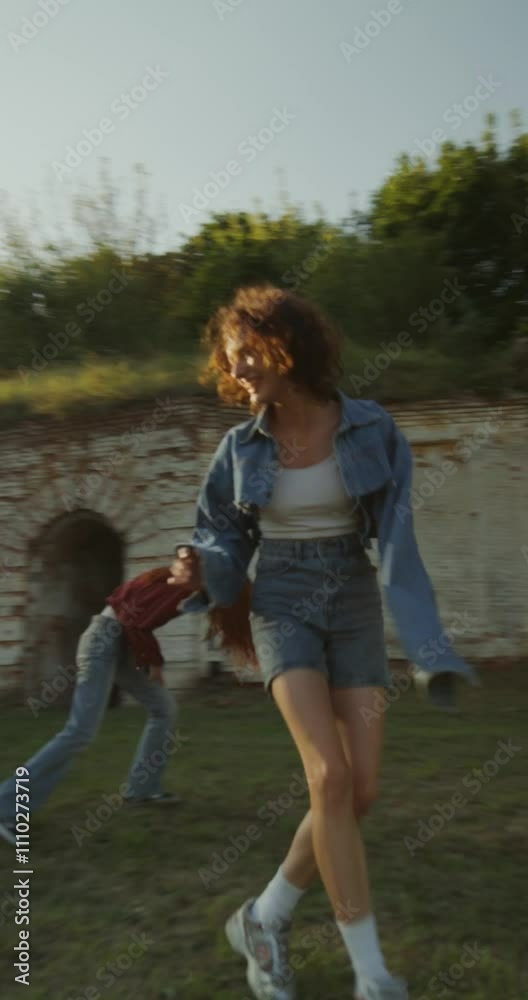 Three young friends are having fun and running around the ruins of a historic building. The fortress walls are overgrown with green vegetation. A sunny summer day Three young friends are having fun and running around the ruins of a historic building. The fortress walls are overgrown with green vegetation. A sunny summer day