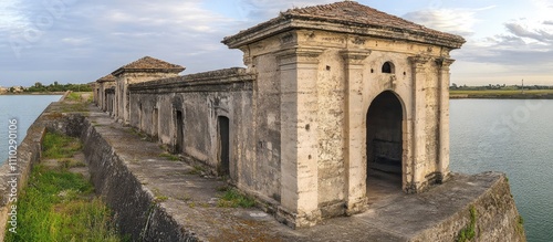 Historic saltworks structures in Marsala showcasing ancient architecture and serene coastal landscape against a cloudy sky.