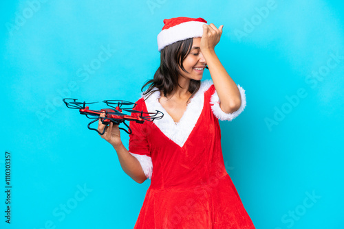 Young woman dressed as mama noel holding a drone isolated on blue background has realized something and intending the solution