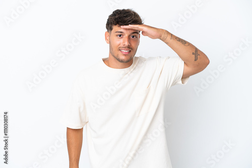 Young caucasian handsome man isolated on white background looking far away with hand to look something