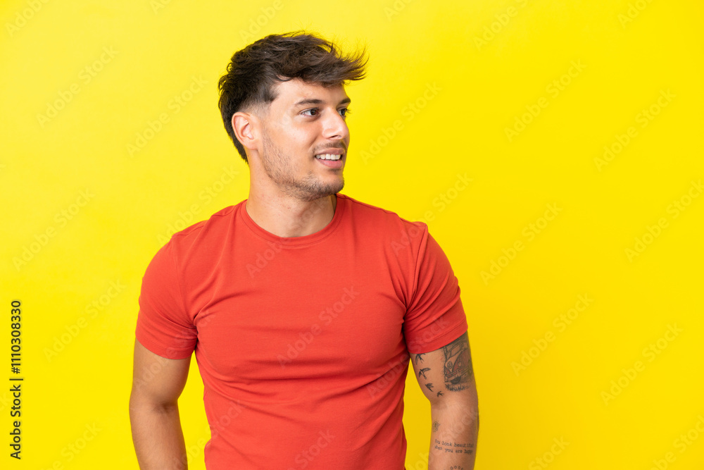 Young caucasian handsome man isolated on yellow background looking to the side and smiling Young caucasian handsome man isolated on yellow background looking to the side and smiling