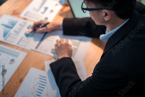 Business analysis action by professional in office space with data reports for strategic insights