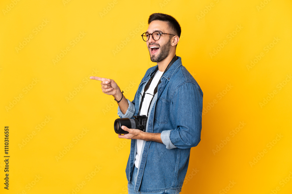Young photographer girl isolated on yellow background pointing finger to the side and presenting a product Young photographer girl isolated on yellow background pointing finger to the side and presenting a product