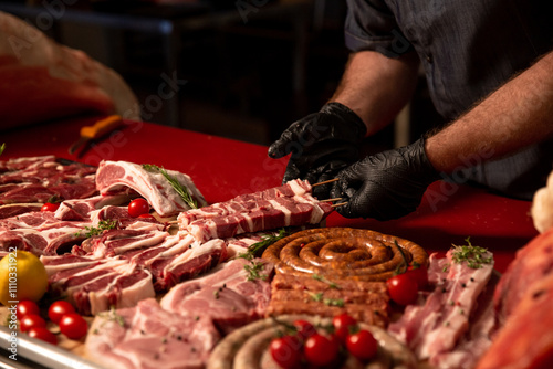 Man hands placing a barbeque preps on a wooden cutting board surrounded by different food preps. Concept of homemage meat food. photo