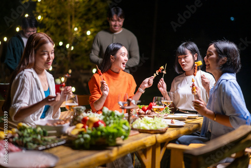 Fotomural A group of women are sitting around a wooden table, eating food and laughing