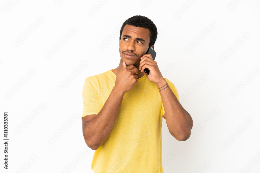 African American handsome man using mobile phone over isolated white background looking up while smiling African American handsome man using mobile phone over isolated white background looking up while smiling