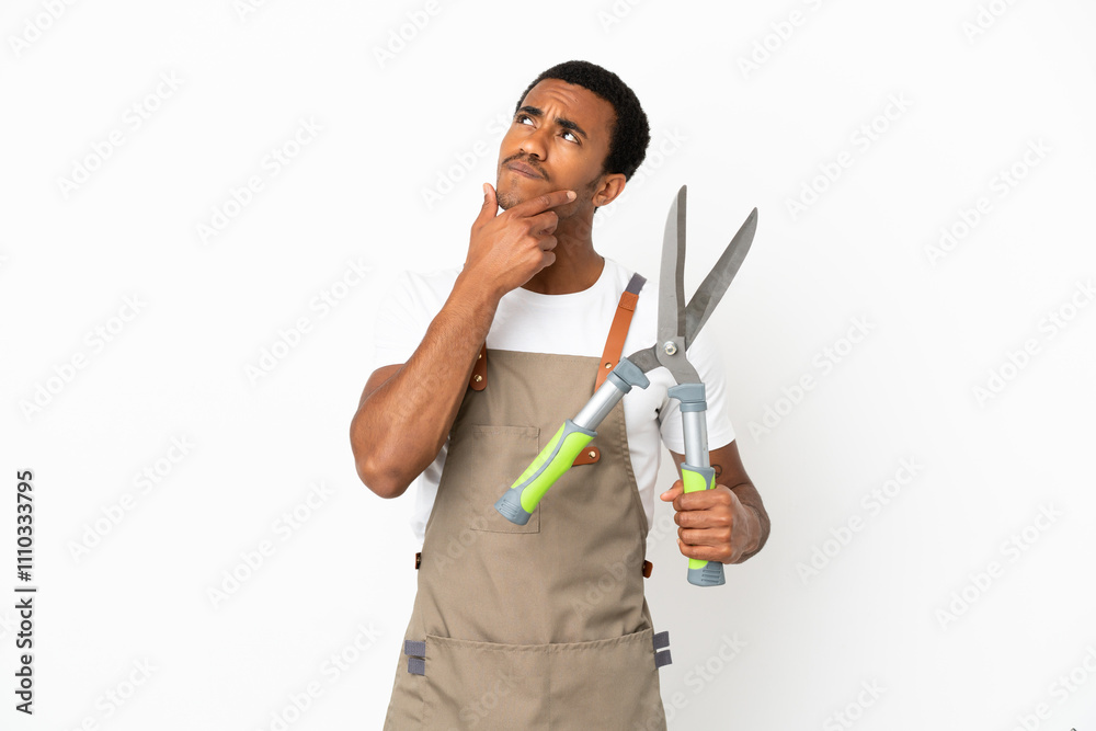 African American gardener man holding pruning shears over isolated white background and looking up African American gardener man holding pruning shears over isolated white background and looking up