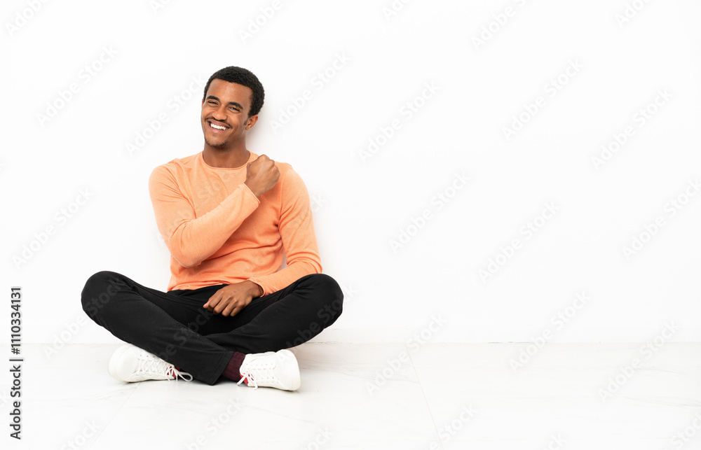 African American man sitting on the floor over isolated copyspace background celebrating a victory African American man sitting on the floor over isolated copyspace background celebrating a victory
