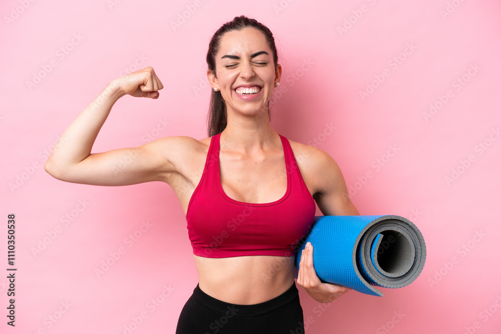 Young sport caucasian woman going to yoga classes while holding a mat isolated on pink background doing strong gesture Young sport caucasian woman going to yoga classes while holding a mat isolated on pink background doing strong gesture