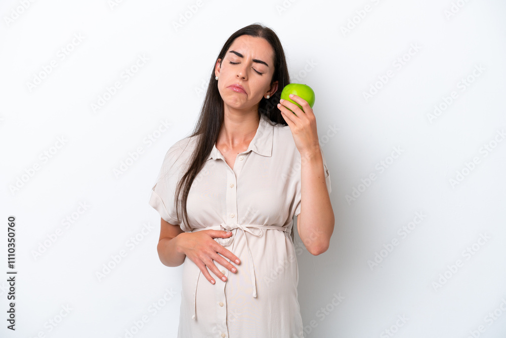 Young caucasian woman isolated on white background pregnant and frustrated while holding an apple Young caucasian woman isolated on white background pregnant and frustrated while holding an apple