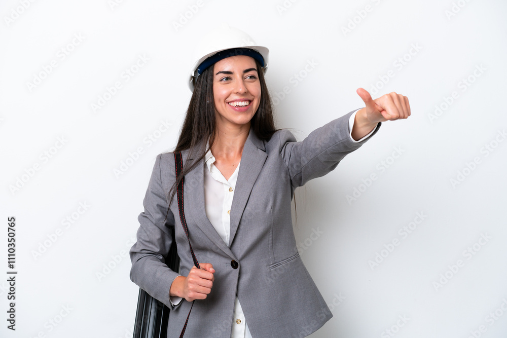 Young architect caucasian woman with helmet and holding blueprints isolated on white background giving a thumbs up gesture