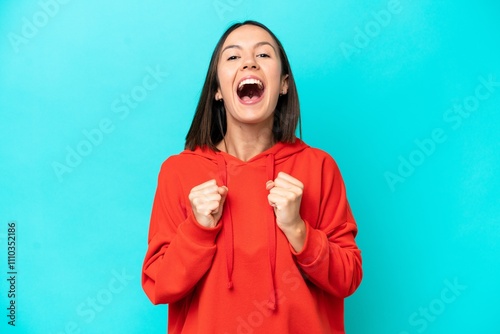 Young caucasian woman isolated on blue background celebrating a victory