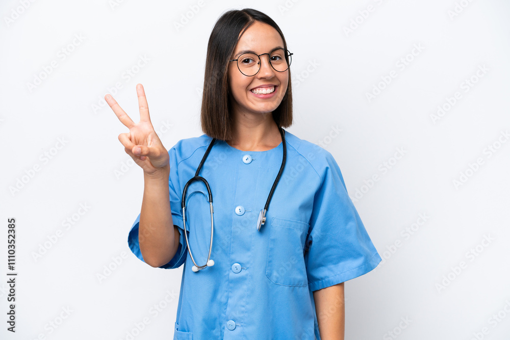 Young surgeon doctor woman isolated on white background smiling and showing victory sign