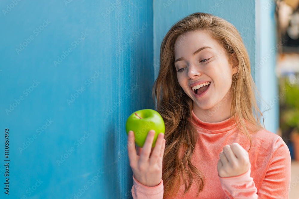 Young redhead woman with an apple at outdoors celebrating a victory Young redhead woman with an apple at outdoors celebrating a victory