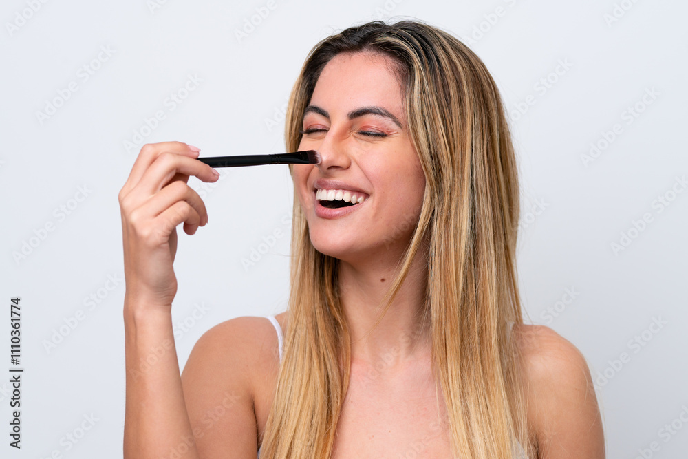 Young caucasian woman isolated on white background holding makeup brush and whit happy expression Young caucasian woman isolated on white background holding makeup brush and whit happy expression