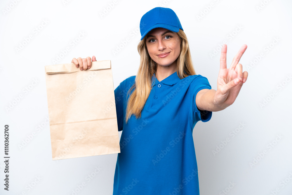 Young Uruguayan woman taking a bag of takeaway food isolated on white background smiling and showing victory sign Young Uruguayan woman taking a bag of takeaway food isolated on white background smiling and showing victory sign