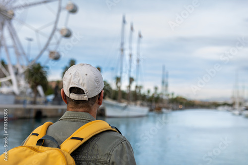 Photography Man with yellow backpack on the promenade of the port of Barcelona