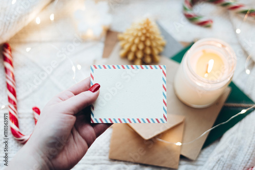 Cozy Christmas card with candle and candy cane on knit blanket photo