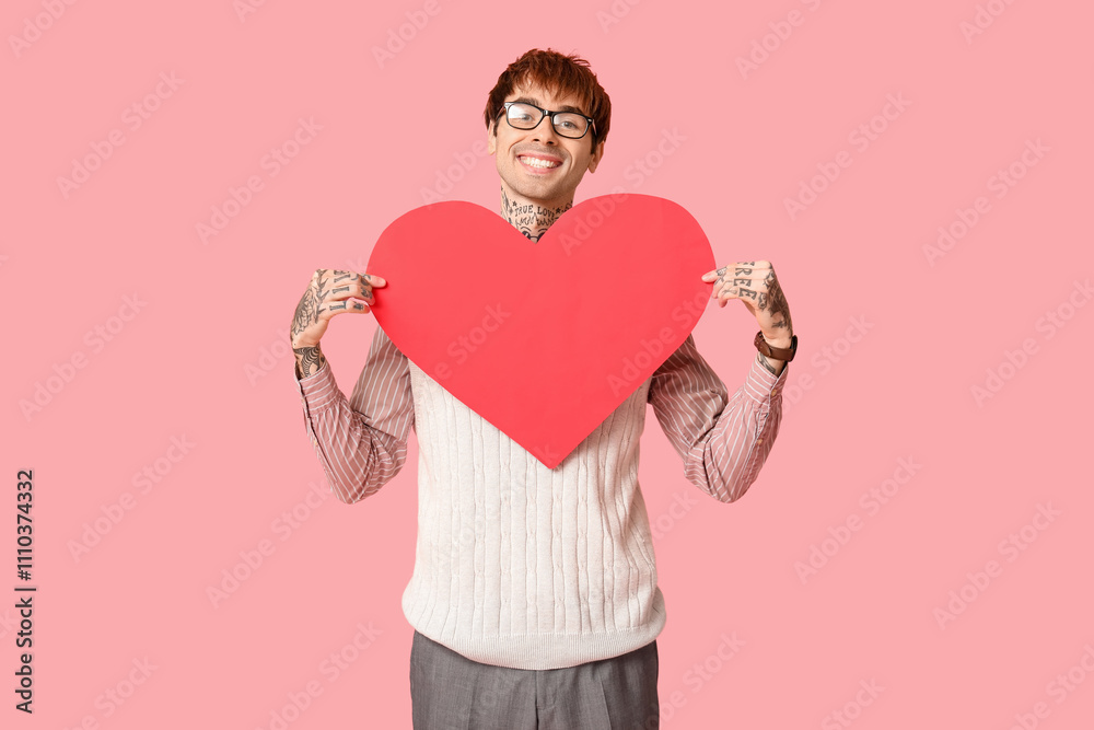 Handsome young man with paper heart on pink background. Valentine's Day celebration Handsome young man with paper heart on pink background. Valentine's Day celebration