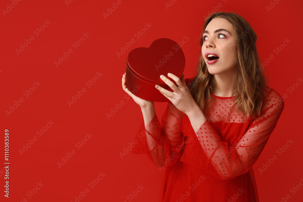 Beautiful young woman with gift box on red background. Valentine's Day celebration