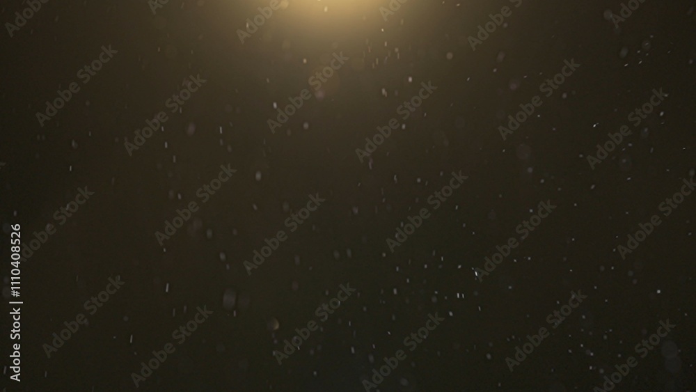 Many sparkling glitters floating in light on black empty background with light from above. Many sparkling glitters floating in light on black empty background with light from above.