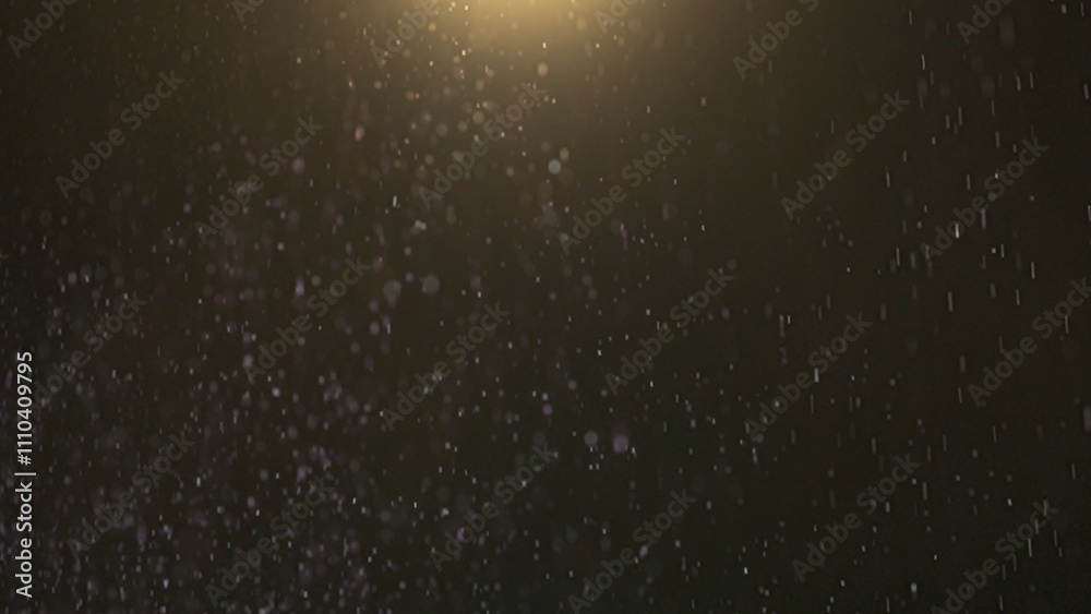 Fototapeta premium Many sparkling purple glitters floating in light on black empty background with light from above.
