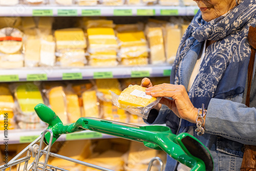 old lady in supermarket choosing cheese from many on the shelves photo