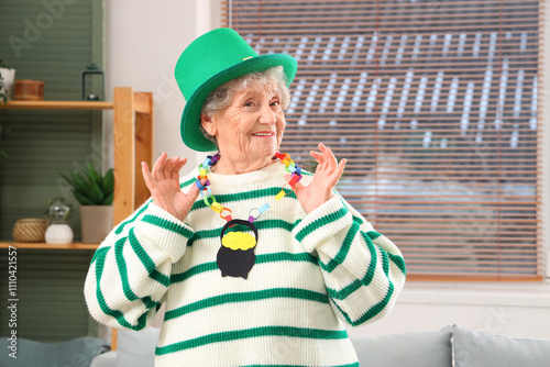 Happy senior woman in leprechaun hat with paper accessory for St. Patrick's Day celebration at home photo