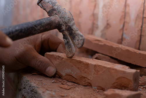 Obraz na płótnie A focused construction worker shaping a brick with a weathered hammer in a dusty environment. w salonie