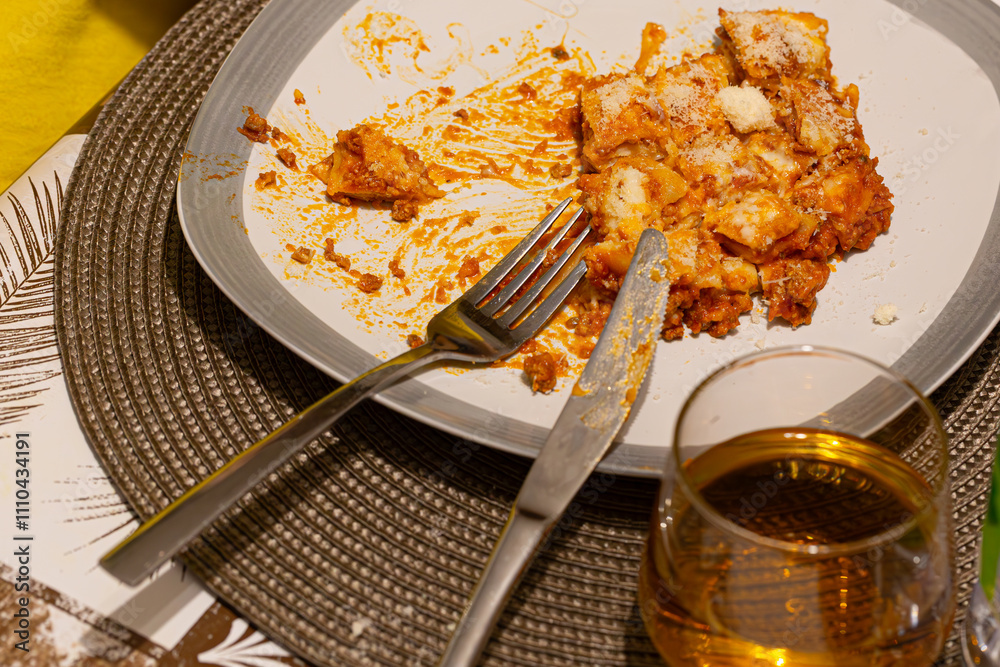 Lasagna served on a gray plate, with cheese melting on top and a bite already taken, highlighting the rich, savory flavor of this beloved dish.