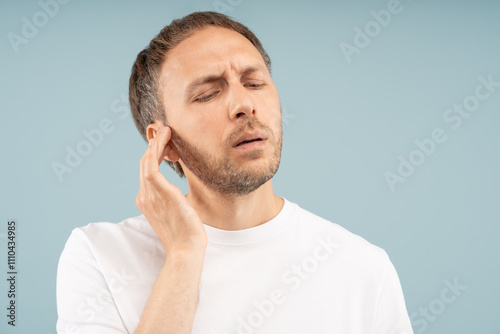 Vászonkép Unwell man feels discomfort in ear stuffiness, mild hearing loss