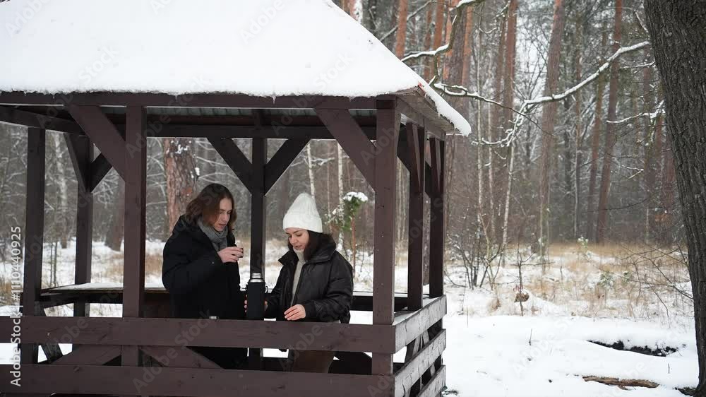 a guy and a girl on a walk in the winter forest drink tea from a thermos a guy and a girl on a walk in the winter forest drink tea from a thermos