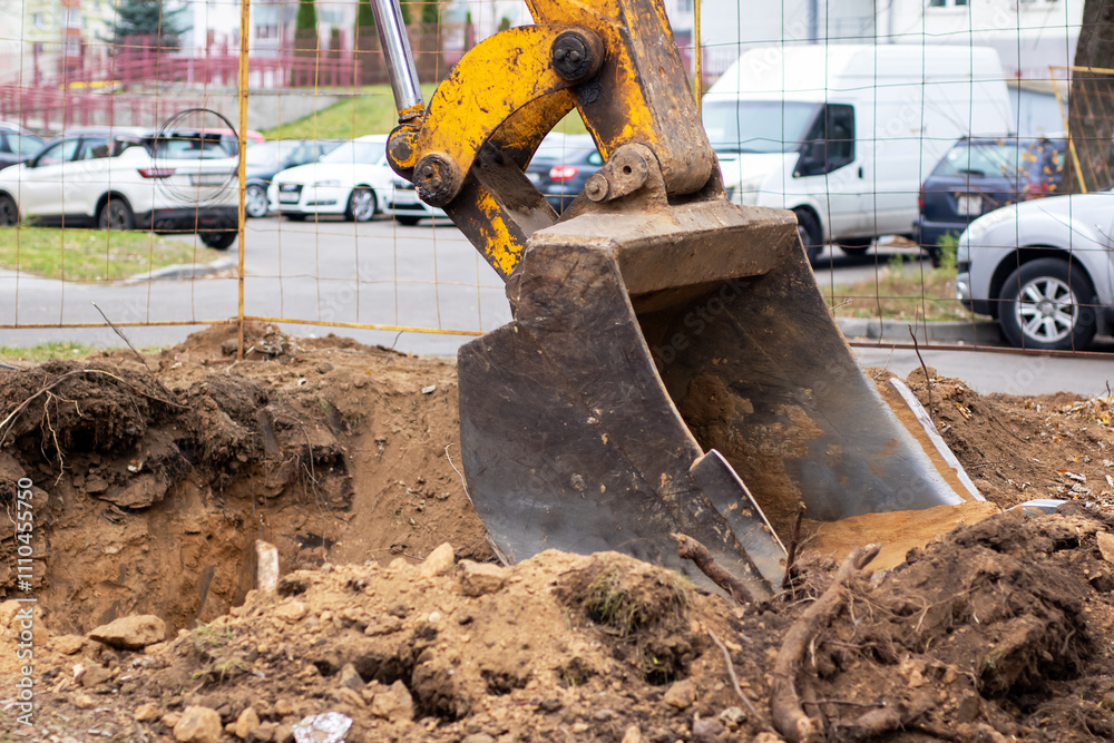 A bright yellow excavator is actively digging a hole in the ground A bright yellow excavator is actively digging a hole in the ground