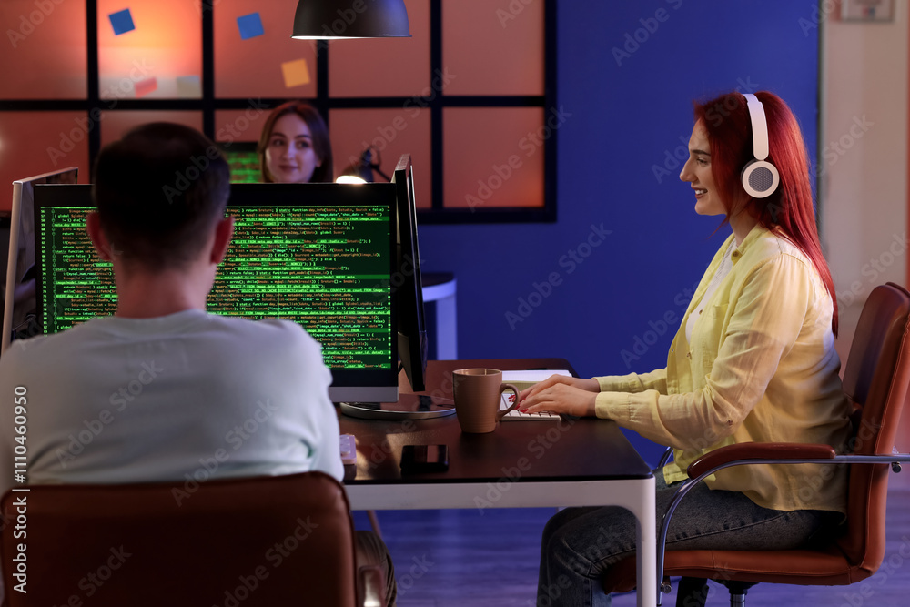 Young female programmer working with computer in office at night Young female programmer working with computer in office at night