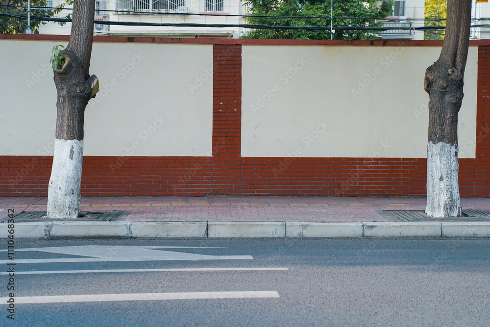 Long old concrete and red brick wall covered with white plaster at city street. Cement fence exterior with copy space and mockup.