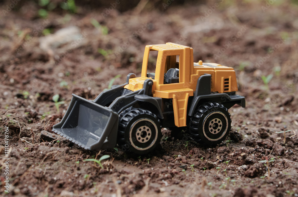 Yellow wheel loader or tractor toy on soil or ground background. construction image concept with heavy equipment. Yellow wheel loader or tractor toy on soil or ground background. construction image concept with heavy equipment.