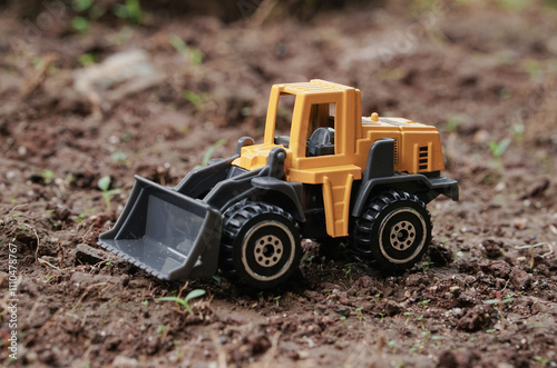 Yellow wheel loader or tractor toy on soil or ground background. construction image concept with heavy equipment.