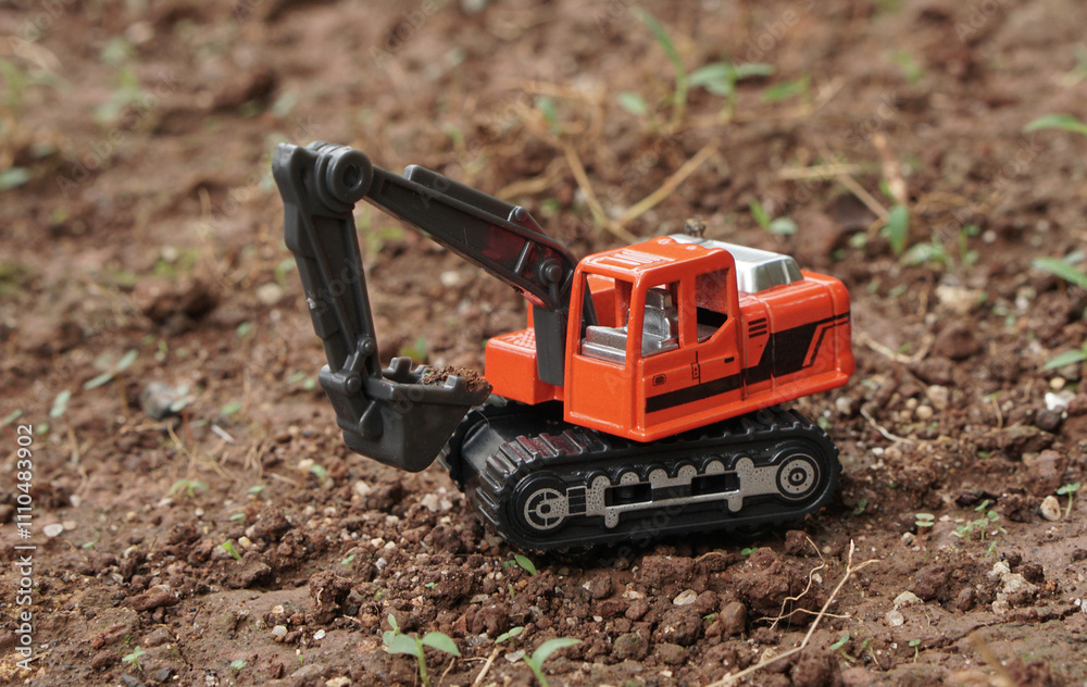 side view of Orange excavator or digger toy excavate on a soil land outdoor. model scale of digger photograp, construction concept. side view of Orange excavator or digger toy excavate on a soil land outdoor. model scale of digger photograp, construction concept.