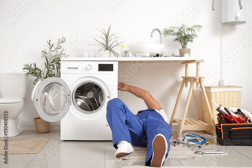 Mature male plumber installing washing machine in bathroom photo