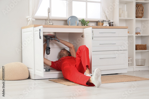 Male plumber fixing sink in...