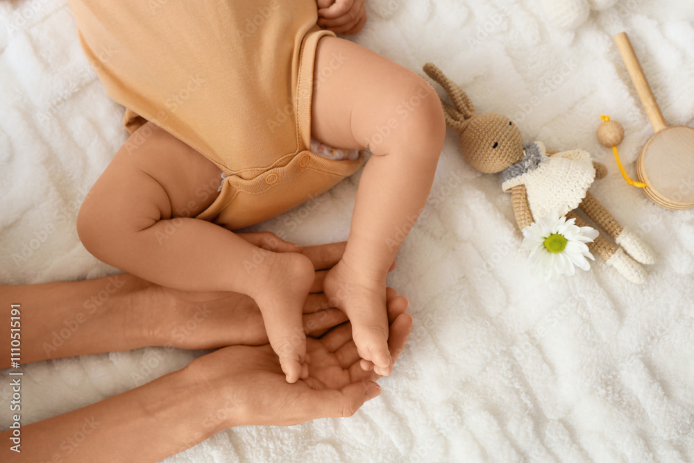 Mother holding her little baby's feet on bed, top view Mother holding her little baby's feet on bed, top view