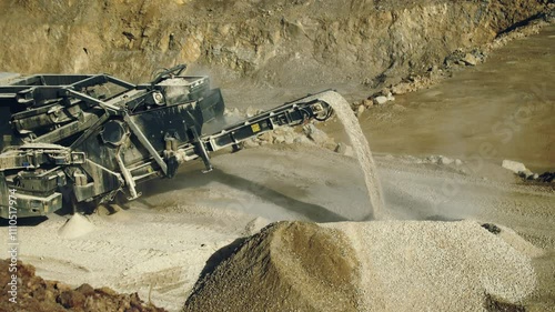 Stone crushing plant machine production line, rocks falling on pile, quarry, open pit, high angle view.