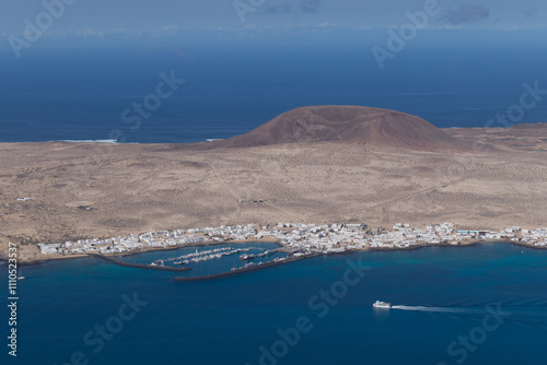 View of La Graciosa Island in the Canary Islands and the main town of Caleto Del Sebo with the ferry heading towards the port.