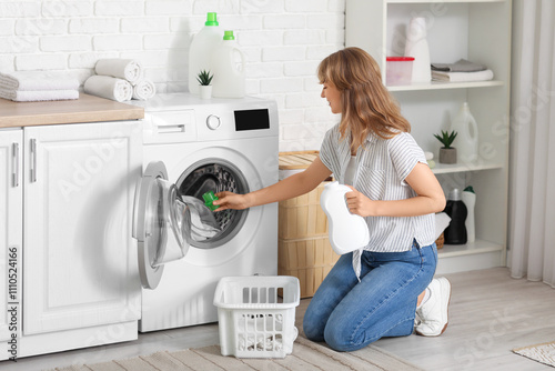 Young woman pouring laundry...